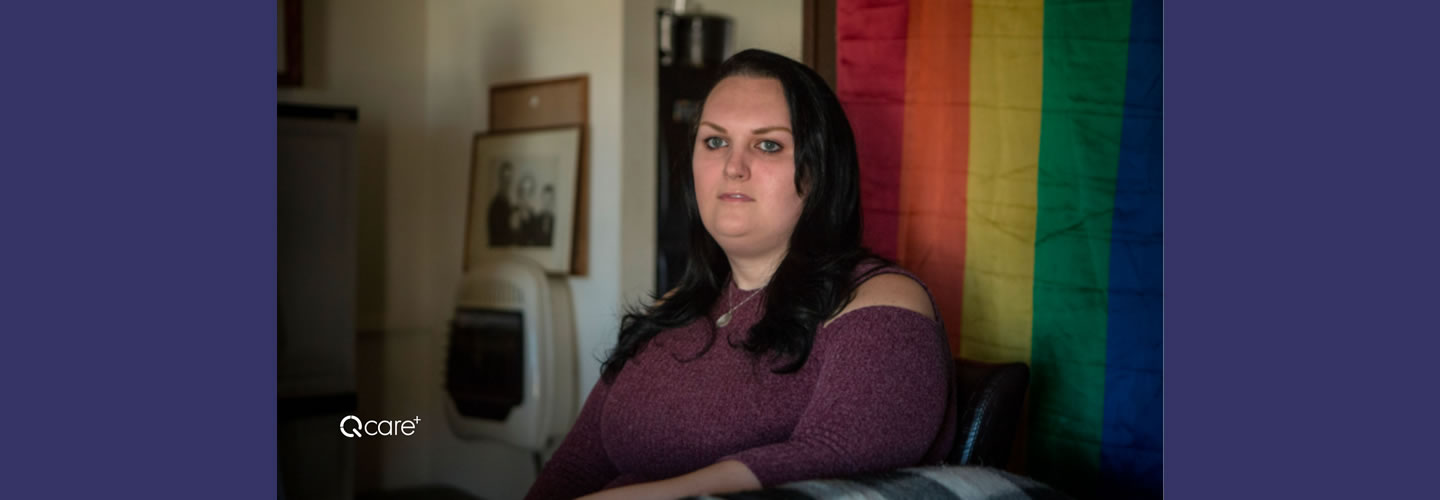 Portrait of a woman in front of an LGBTQ+ flag